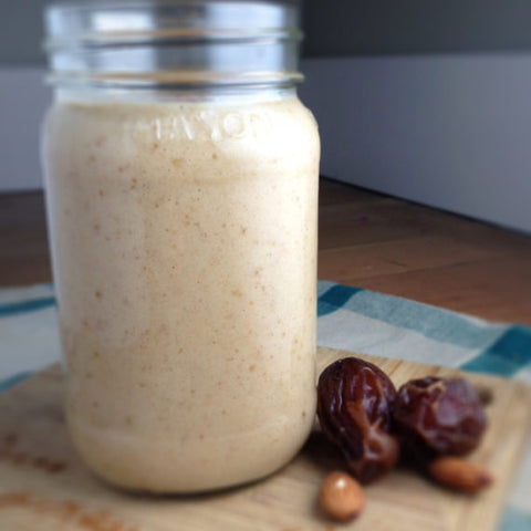 Mason jar of creamy date and almond smoothie beside dates and almonds
