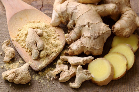Fresh ginger root, ginger slices and a wooden spoon of ground ginger