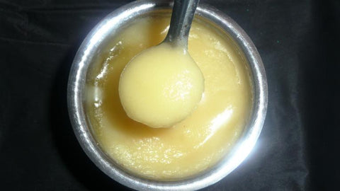 Spoonful of ghee lifted from a steel bowl of ghee