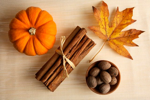 Small pumpkin, bundle of cinnamon sticks, whole nutmegs and an autumn maple leaf