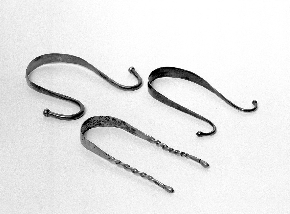 Three curved silver tongue scrapers on a plain white background, one with twisted handles