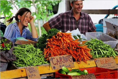 Farmers market stall with bunches of carrots and green beans with handwritten price signs