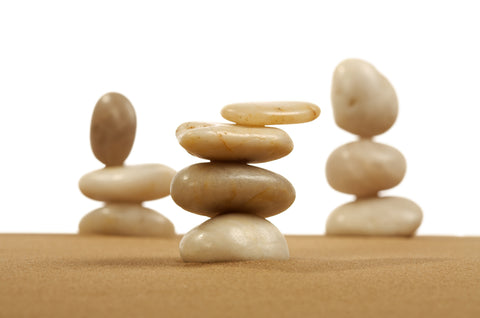 Three stacks of smooth balanced pebbles standing on sand