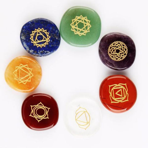 Seven polished chakra gemstones in a circle, each engraved with a gold chakra symbol