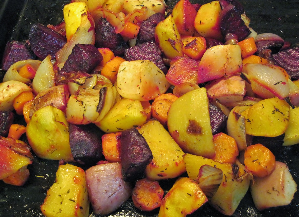 Roasted chunks of beet, turnip, rutabaga, carrot and onion with dried herbs in a dark roasting pan