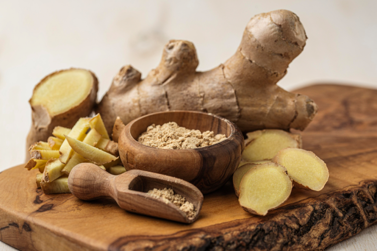 Fresh ginger root with slices, chopped pieces and ground ginger in a wooden bowl and scoop